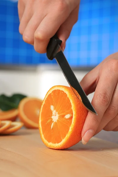 stock image Female chopping juicy orange on the kitchen.