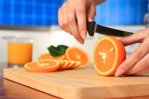 stock image Female chopping juicy orange on the kitchen.