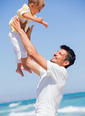 Father and son having fun on beach clipart