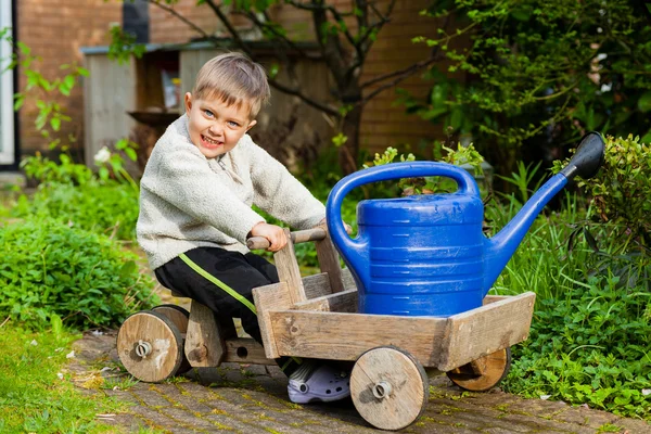 Bonito menino brinca com ferramentas de brinquedo no jardim . — Fotografia de Stock
