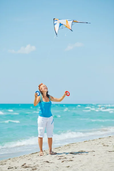 Mujer en la playa jugando con una cometa colorida — Foto de Stock