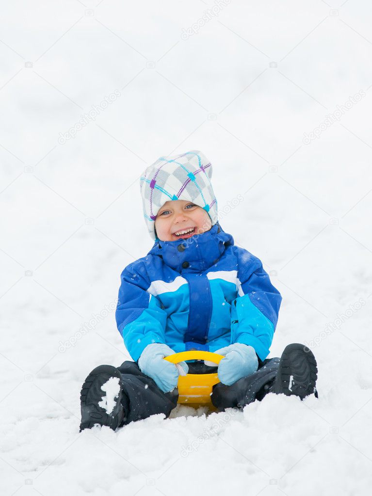 The boy goes for a drive on an snow slope.