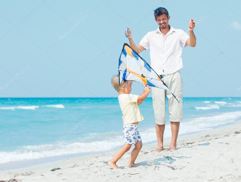 Boy with father on beach playing with a kite