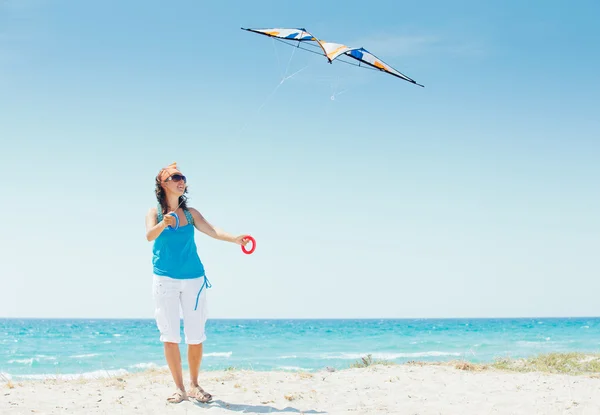 Woman on beach playing with a colorful kite — Stock Photo, Image