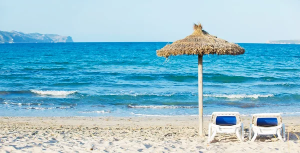 Tropischer Strand mit Sonnenschirm und Liegestühlen — Stockfoto