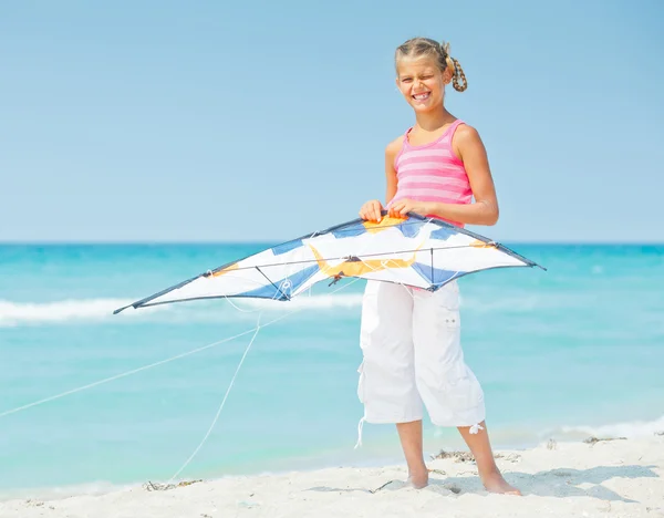 Χαριτωμένο κορίτσι στην παραλία που παίζει με ένα πολύχρωμο χαρταετό — Φωτογραφία Αρχείου