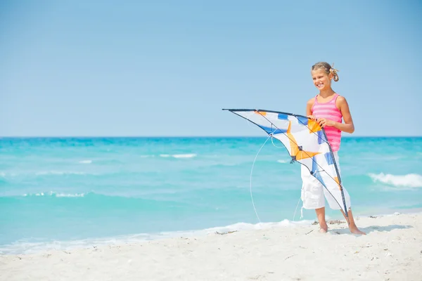 Милая девушка на пляже играет с разноцветным воздушным змеем — стоковое фото