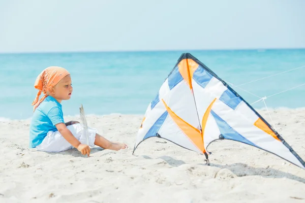 Χαριτωμένο αγόρι στην παραλία που παίζει με ένα πολύχρωμο χαρταετό — Φωτογραφία Αρχείου