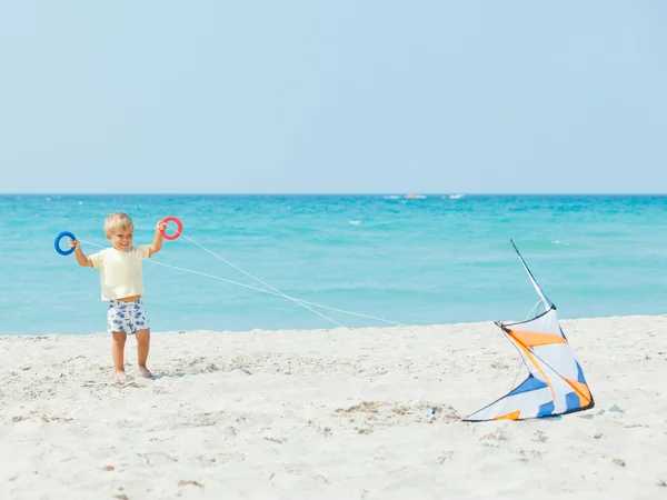 Netter Junge am Strand, der mit einem bunten Drachen spielt — Stockfoto