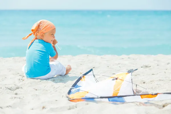 Söt pojke på stranden spelar med en färgglad drake — Stockfoto