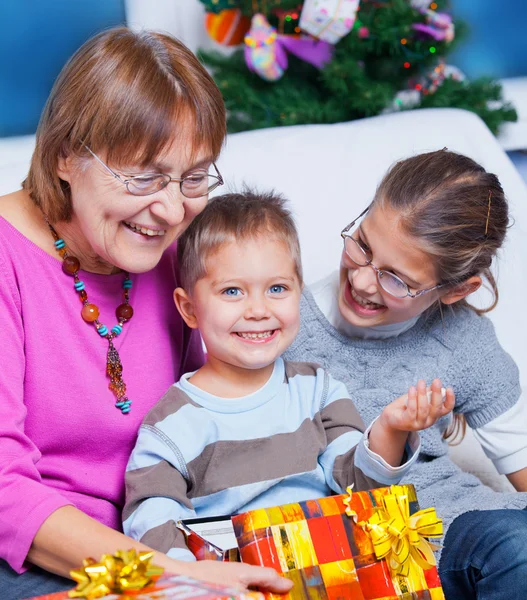 Oma en haar twee kleinkinderen met geschenken — Stockfoto