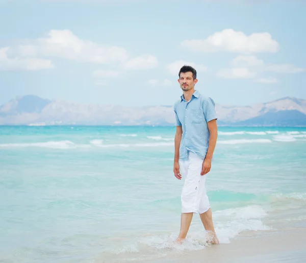 Молодий чоловік ходить біля блакитного моря . — стокове фото
