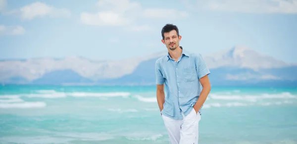 Jonge man lopen in de buurt van blauwe zee. — Stockfoto
