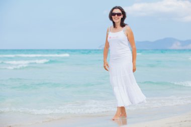 Young woman walking near blue sea.