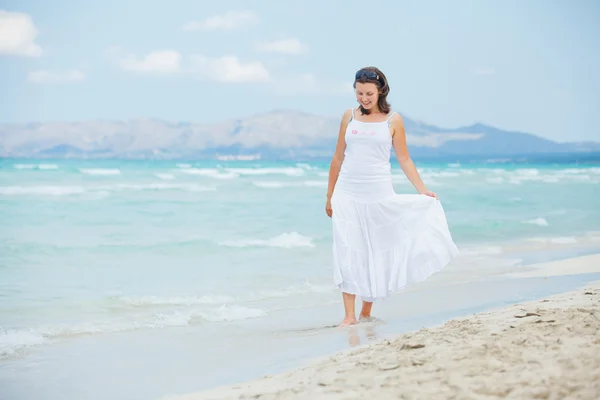 Młoda kobieta spaceru w pobliżu błękitne morze. — Zdjęcie stockowe