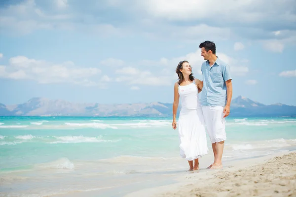 Joyeux jeune couple marchant sur la plage — Photo