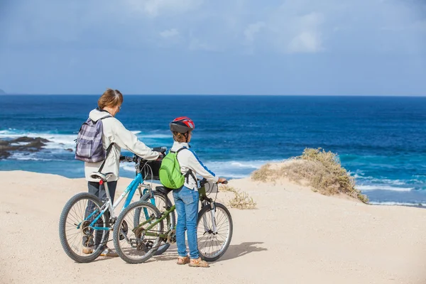 Girl and her grandmother on bikes on the beach — Stock Photo, Image