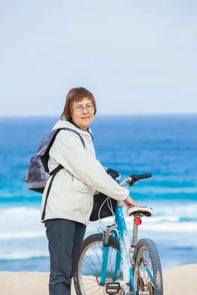 Une gentille dame âgée en vélo sur la plage . — Photo