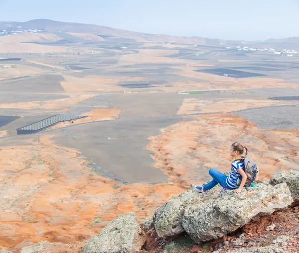 Девушка, сидящая на краю скалы, глядя на небо — стоковое фото