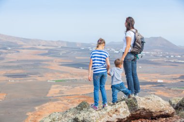Mother and her child standing on cliff's edge clipart