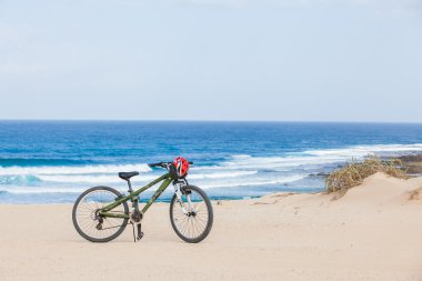 Bicycle with helmet, stand on the beach. clipart