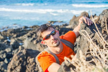 Young man in glasses with backpack climbing clipart