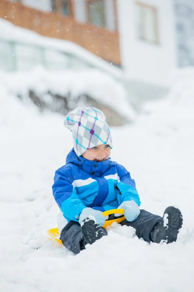 De jongen gaat voor een station op een helling van de sneeuw. — Stockfoto