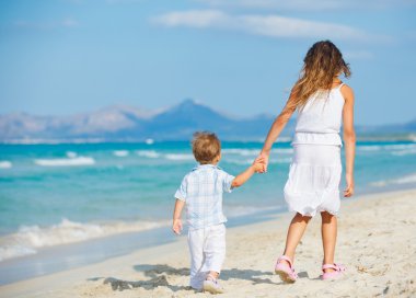 Young girl and boy playing happily at pretty beach clipart