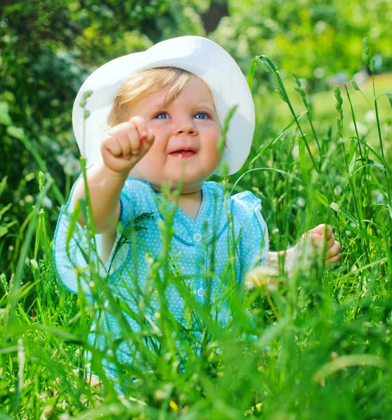 Little girl sitting in the grass in the park — Stock Photo, Image