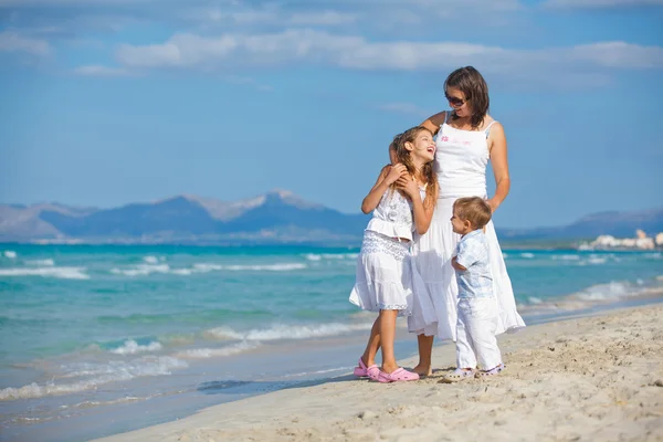 Joven madre con sus dos hijos en vacaciones en la playa — Foto de Stock