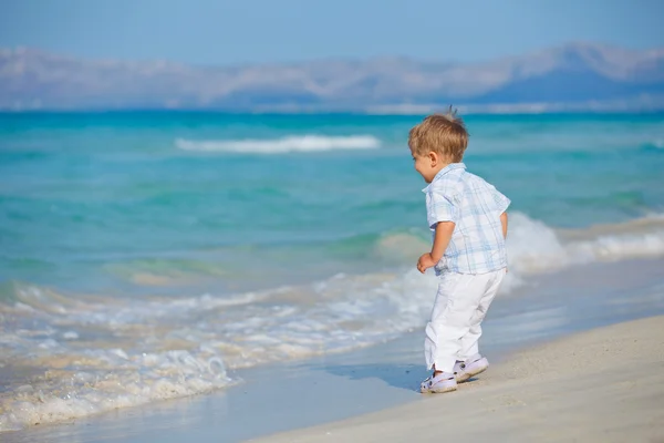 Jovem menino bonito jogando alegremente na praia bonita — Fotografia de Stock