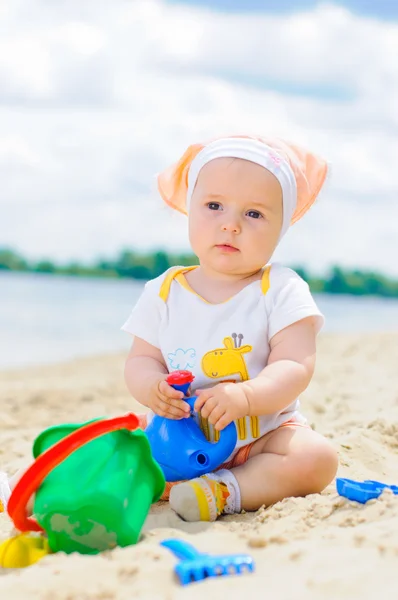Niedliches kleines Mädchen spielt am Strand mit Sand. — Stockfoto