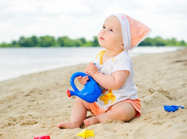 Baby flicka som leker på stranden med sand. — Stockfoto