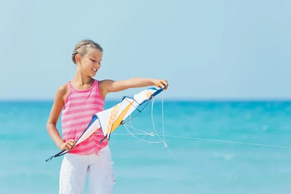 Милая девушка на пляже играет с разноцветным воздушным змеем — стоковое фото