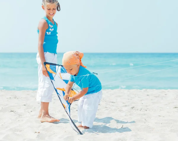 Junge mit Schwester am Strand spielt mit einem Drachen — Stockfoto