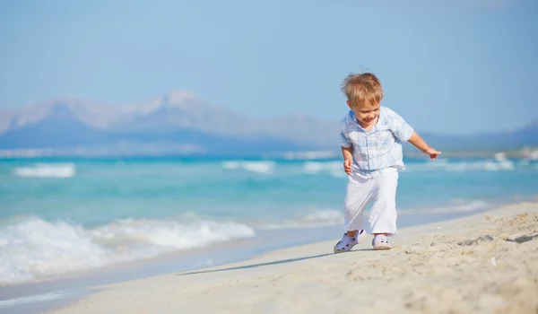Jovem menino bonito jogando alegremente na praia bonita — Fotografia de Stock