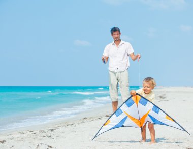Boy with father on beach playing with a kite clipart