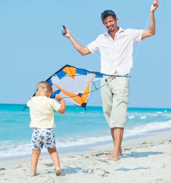 Мальчик с отцом на пляже играет с воздушным змеем — стоковое фото