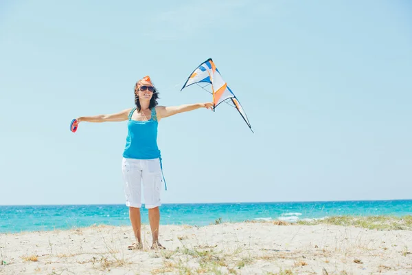Женщина на пляже играет с цветным воздушным змеем — стоковое фото