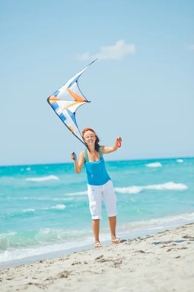 Γυναίκα στην παραλία που παίζει με ένα πολύχρωμο χαρταετό — Φωτογραφία Αρχείου