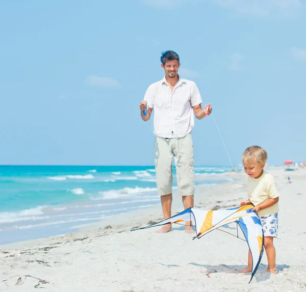 Niño con padre en la playa jugando con una cometa —  Fotos de Stock