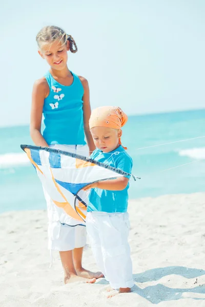 Niño con hermana en la playa jugando con una cometa — Foto de Stock
