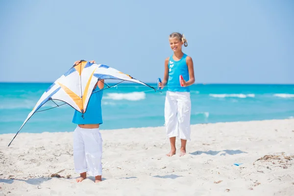 Girl with brother on beach playing with a kite — Stock Photo, Image