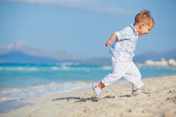 Молодой милый мальчик счастливо играет на красивом пляже — стоковое фото