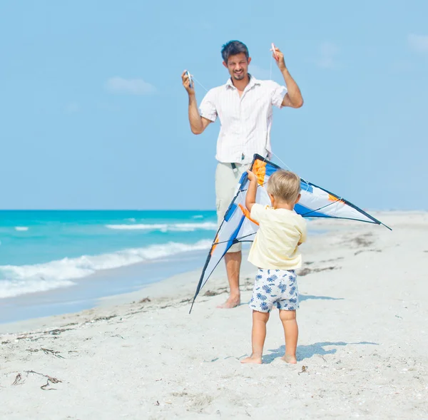 Pojke med far på stranden spelar med en drake — Stockfoto