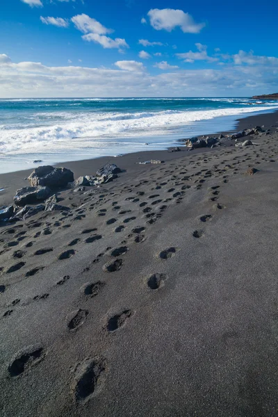 Spiaggia esotica con sabbia nera e impronte — Foto Stock