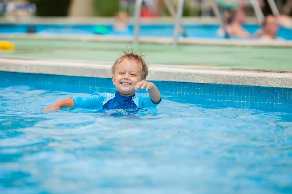 Pojke spelar i en pool med vatten — Stockfoto
