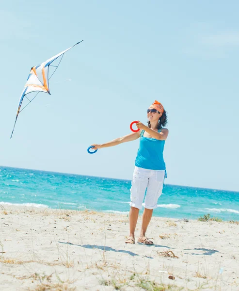 Donna sulla spiaggia a giocare con un aquilone colorato — Foto Stock