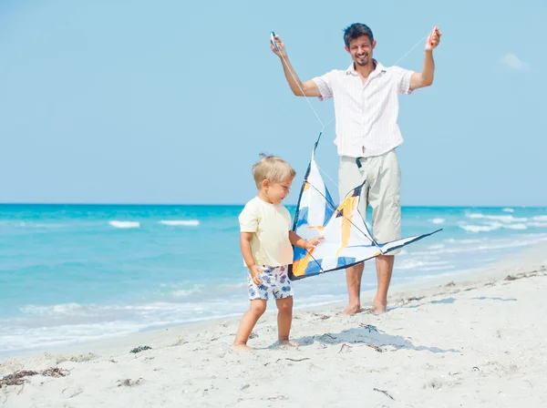 Chłopiec z ojcem na plaży gra z latawcem — Zdjęcie stockowe
