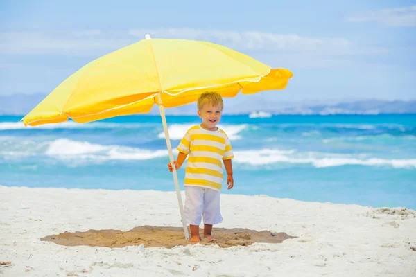 Büyük tropikal plaj şemsiyesi olan çocuk — Stok fotoğraf